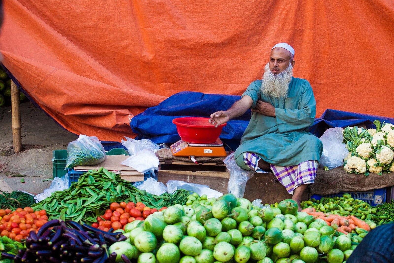 Vegetable seller weighing fresh produce at a market in Bangladesh