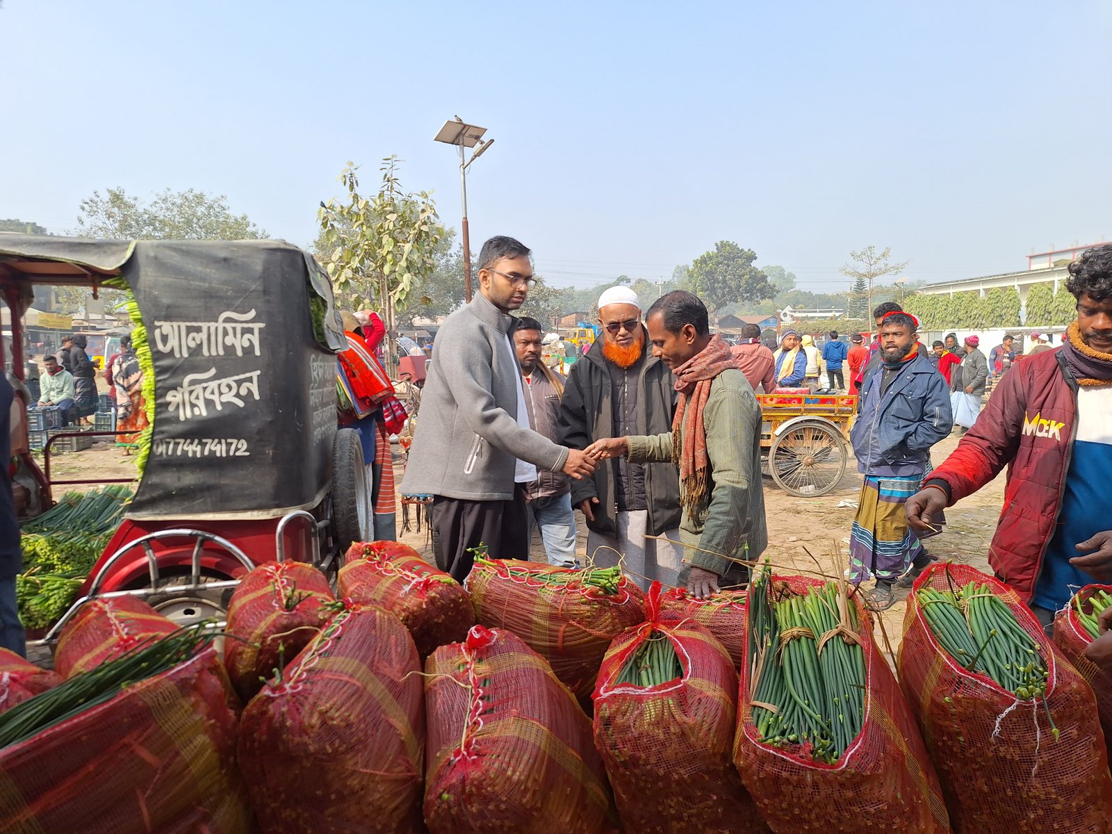 Buyers and growers meeting beside fresh produce at a wholesale market in Bangladesh