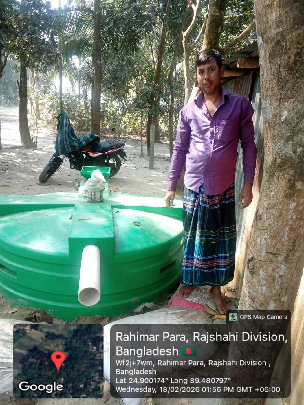 Man standing beside a green household biodigester