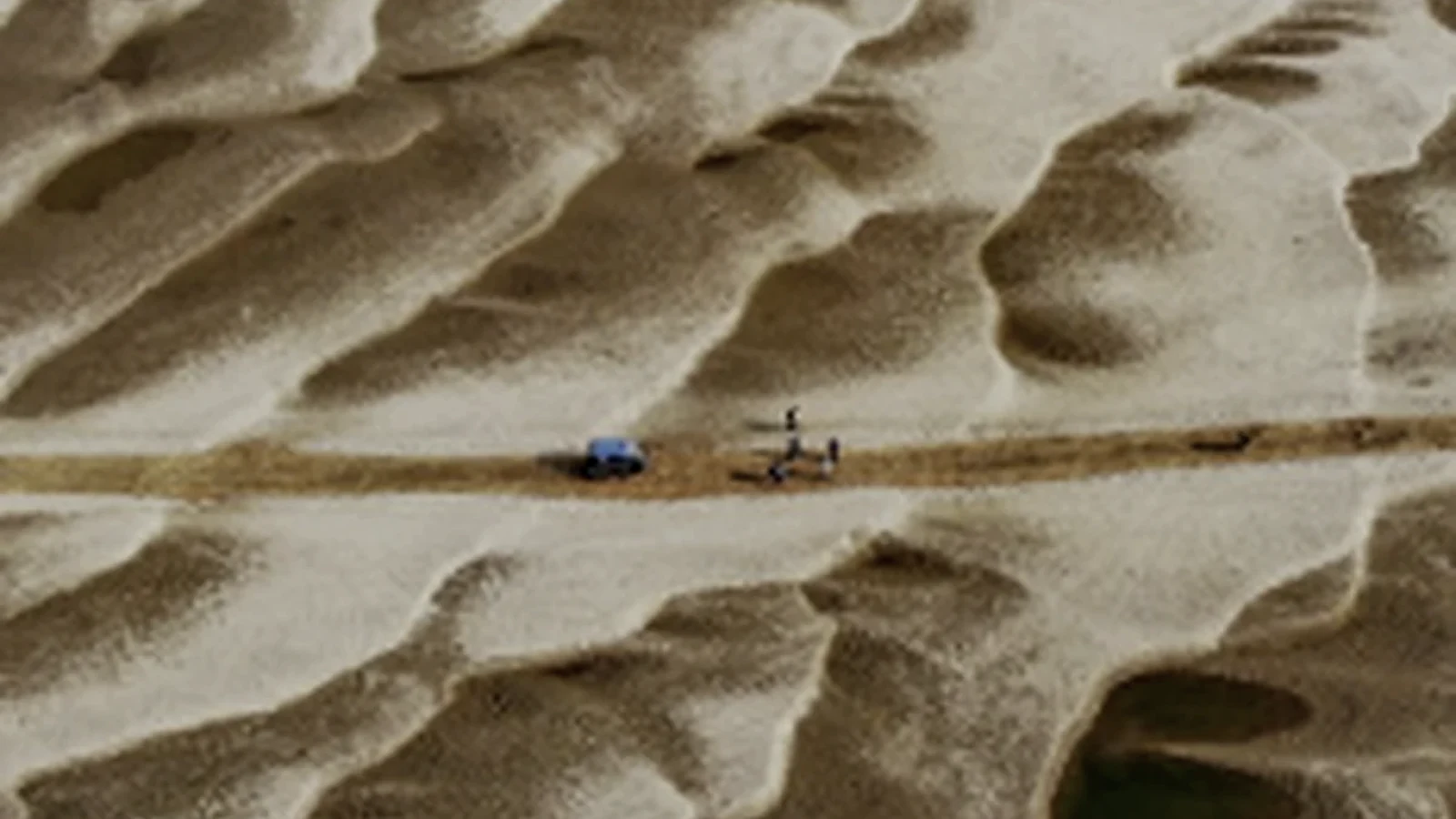 Patterned exposed char sand crossed by a narrow route