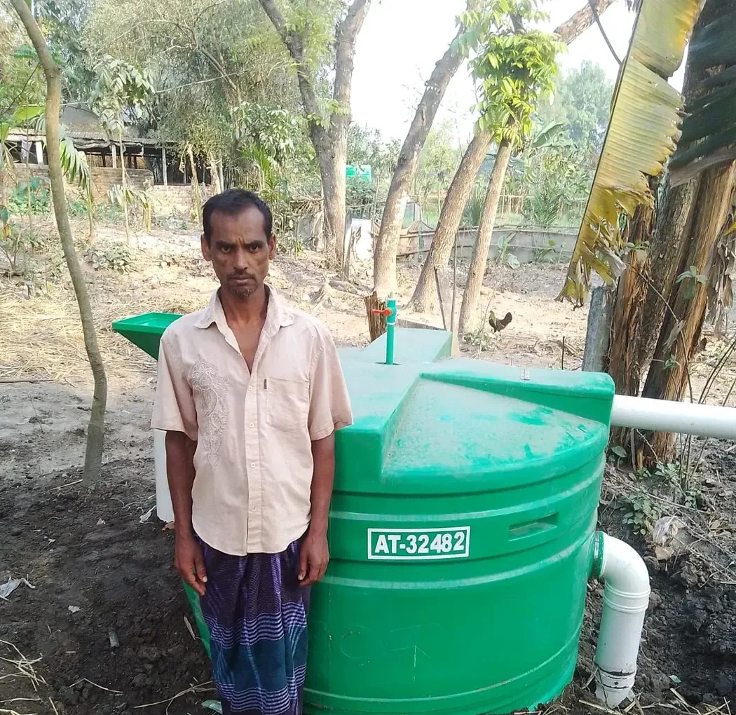 A man standing beside a household biodigester installation